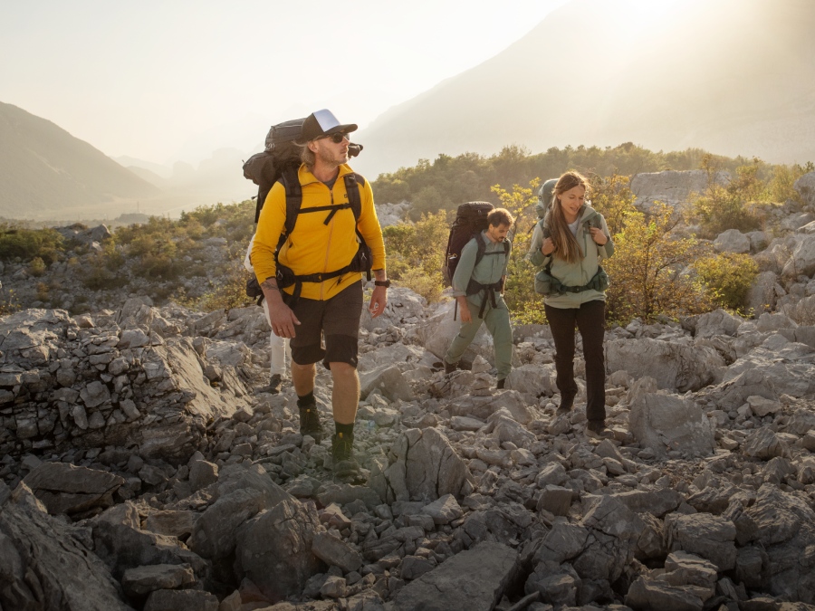 Three hikers with trekking equipment in the mountains